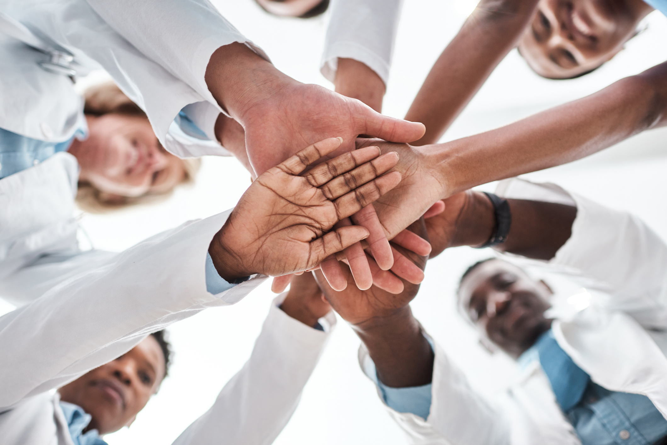 Closeup shot of a group of medical practitioners joining their hands together in a huddle